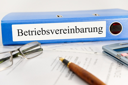 Bild eines Ordners Betriebsvereinbarung, Brille, Füller und Taschenrechner